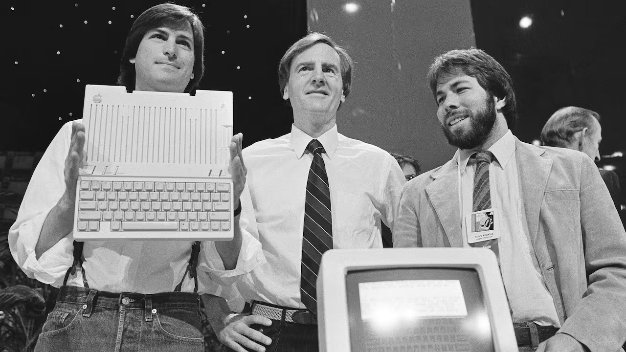 Steve Jobs, John Sculley and Steve Wozniak presenting the Apple IIc on stage.