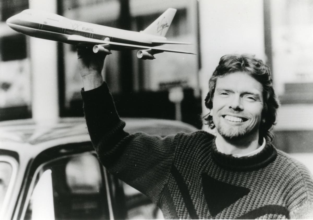 Richard Branson holding a model Virgin Atlantic aircraft above his head.